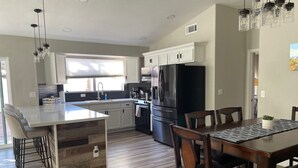 Una cocina moderna con una isla central, electrodomésticos de acero inoxidable y un comedor con sillas de madera.