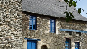 Un edificio de piedra con puertas y ventanas azules, rodeado de macetas con plantas y flores.