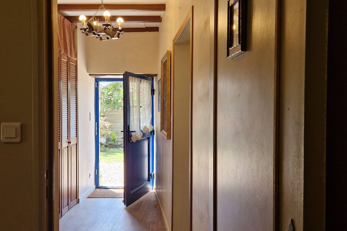 A hallway with wooden flooring, a chandelier, and a door with a handle.