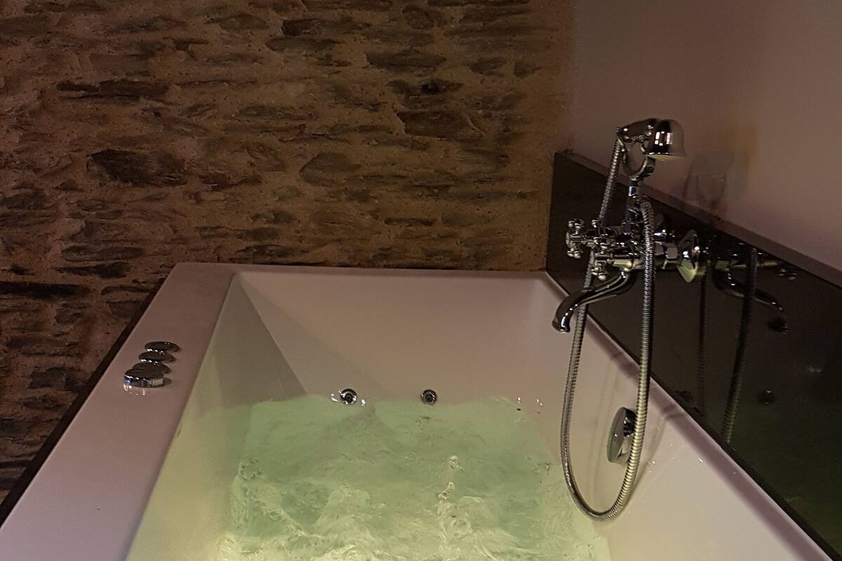 A bathtub with a shower head and controls.