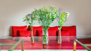Un tavolo in vetro con tre vasi di fiori davanti a un divano rosso.
