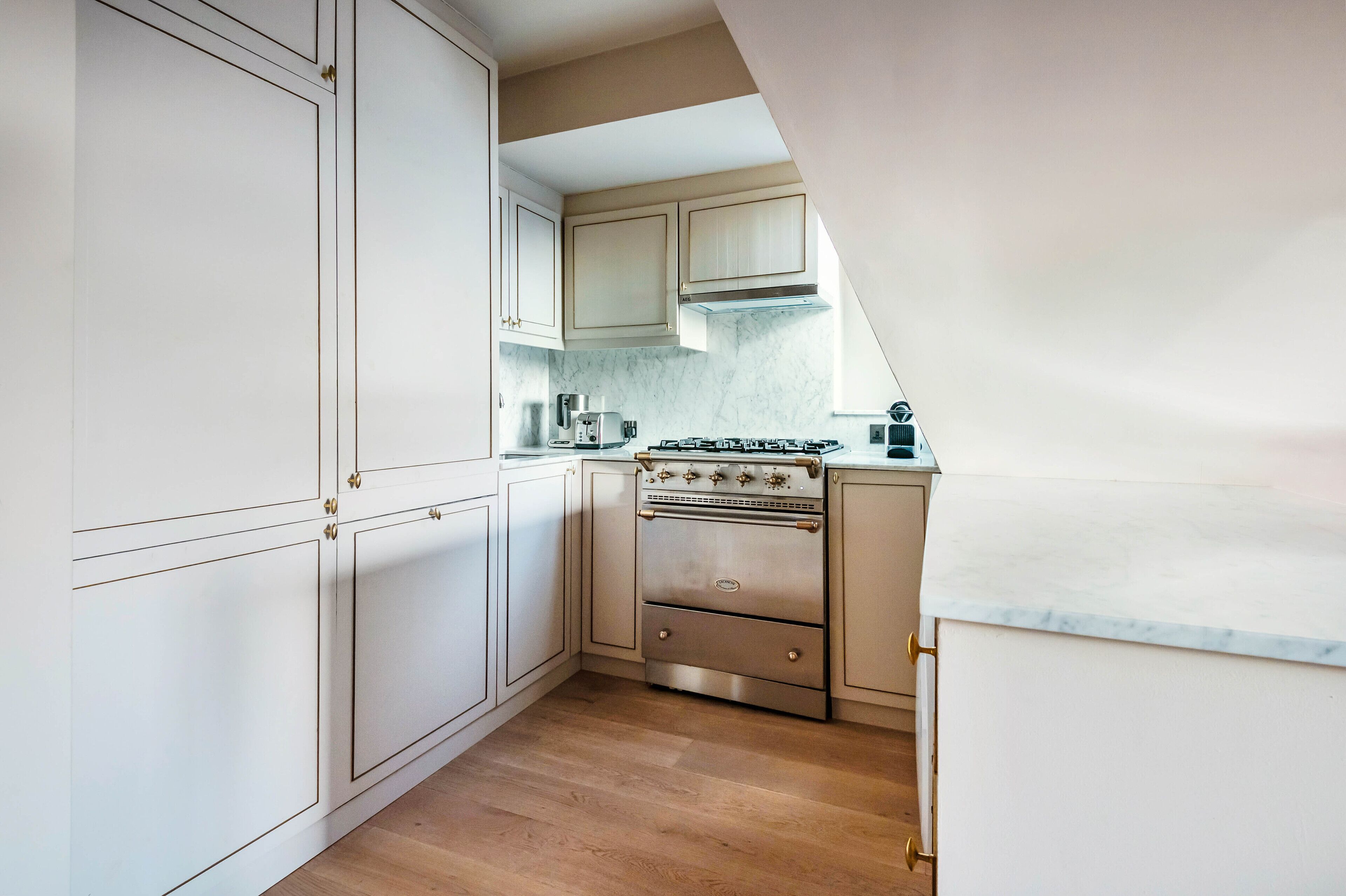 A kitchen with white cabinets, a stainless steel stove, and a marble countertop.