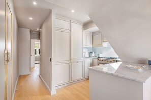 Een moderne keuken met witte kastjes, een marmeren aanrechtblad en een inbouwoven.