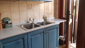 A kitchen with blue cabinets, a double sink, and a white countertop. - Cozy home for families in Pisa (Pisa)