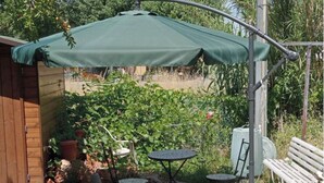 A patio with a green umbrella, two tables, and chairs. - Cozy home for families in Pisa (Pisa)