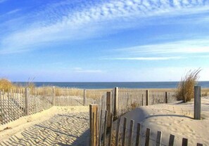 Une plage de sable avec une clôture en bois et un ciel dégagé.