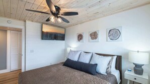 A bedroom with a bed, a ceiling fan, a TV mounted on the wall, and artwork. - Mountain Views Full Kitchen Indoor Pool Access (Gatlinburg)