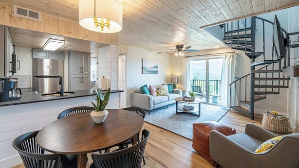 A modern interior with a dining area, kitchen, living room, and a staircase. - Mountain Views Full Kitchen Indoor Pool Access (Gatlinburg)