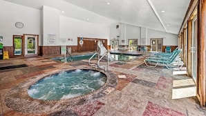 A large indoor pool area with a hot tub, lounge chairs, and a wooden wall. - Mountain Views Full Kitchen Indoor Pool Access (Gatlinburg)