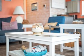 A living room with a white coffee table, a blue basket, and a glass bowl on the table.