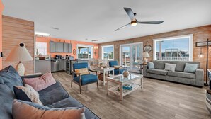 Een moderne woonkamer met een bank, fauteuils, een salontafel en een eethoek.
