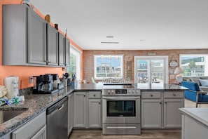 A modern kitchen with grey cabinets, a stainless steel stove, and a large island with a sink.