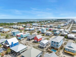 A coastal residential area with multiple houses, some with elevated structures, and a clear view of the ocean.