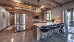 A modern kitchen with wooden cabinets, stainless steel appliances, and a central island with bar stools.