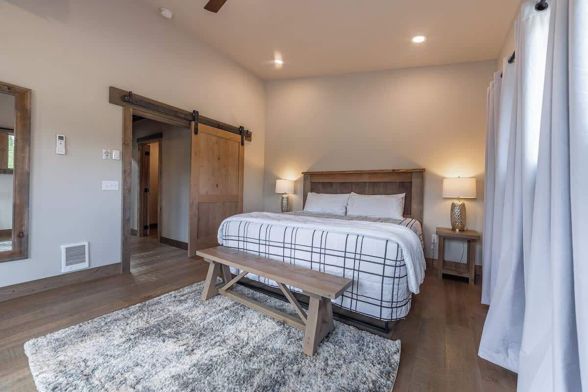 A bedroom with a large bed, wooden bench, and a sliding barn door.