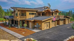A two-story log cabin with a covered front porch, a garage, and a driveway.
