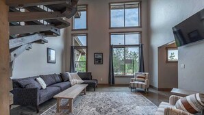 A spacious living room with a large window, a sofa, a coffee table, and a TV.