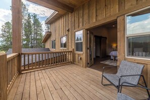 Une terrasse en bois avec une chaise, une porte donnant sur l’intérieur et une vue sur les arbres.