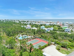 An aerial view of a residential area with houses, a tennis court, and a swimming pool.