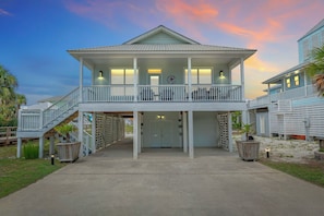 A two-story building with a balcony, a staircase, and a door with a sign.