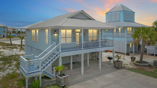 A coastal house with a covered porch, a staircase, and a small tower.