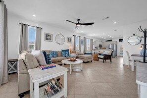 A spacious living area with a sofa, coffee table, and a dining table. - Newly remodeled beach home seconds from the Beach, pool, tennis and golf. (Gulf Shores)