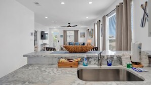 A modern kitchen with a marble countertop, a built-in sink, and a central island with a woven bowl.