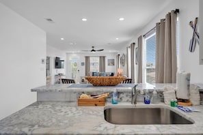 A modern kitchen with a marble countertop, a built-in sink, and a central island with a woven bowl.