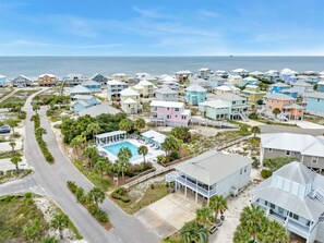 A coastal residential area with houses, a swimming pool, and a road. - Newly remodeled beach home seconds from the Beach, pool, tennis and golf. (Gulf Shores)