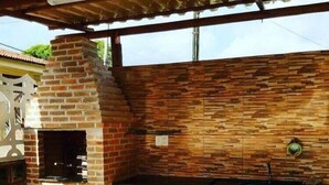 Una cocina exterior con horno de ladrillo, un fregadero y suelo de baldosas.