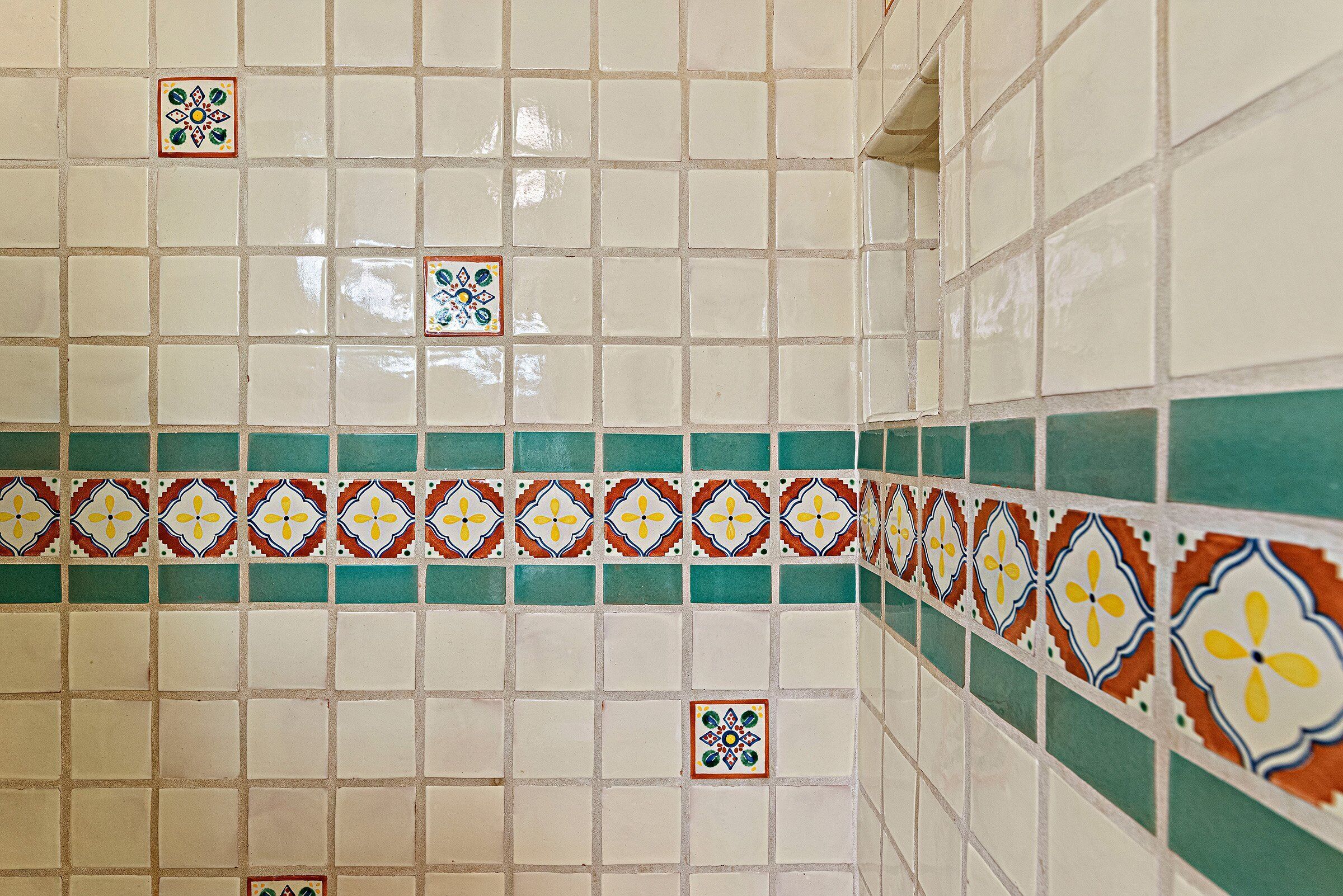 A tiled wall with a pattern of white tiles and a decorative border.