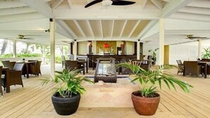 A covered outdoor seating area with wooden flooring, potted plants, and a central fire feature. - Beautiful 2 bed/2 bath Ocean view  - TripAdvisor winner 2016,2017,2018 and 2019! (Wheeland Settlement)