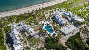 An aerial view of a resort with multiple buildings, a central pool, and a beach. - Beautiful 2 bed/2 bath Ocean view  - TripAdvisor winner 2016,2017,2018 and 2019! (Wheeland Settlement)