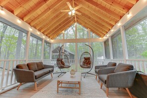 A covered porch with wicker furniture, a ceiling fan, and string lights.