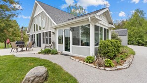 Una casa a due piani con un portico coperto, un patio con mobili da esterno e un giardino curato.