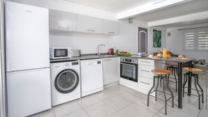 A modern kitchen with a built-in washing machine, microwave, and oven. - Un séjour idéal à découvrir  (SAINTE ANNE)