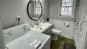 Un baño con lavadora, lavamanos, inodoro y ventana con vistas.