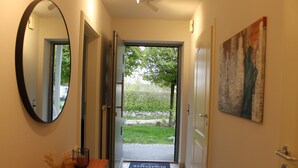 A hallway with a mirror, a doormat, and a painting on the wall. - Luxury apartment for up to 2 people (Flensburg)