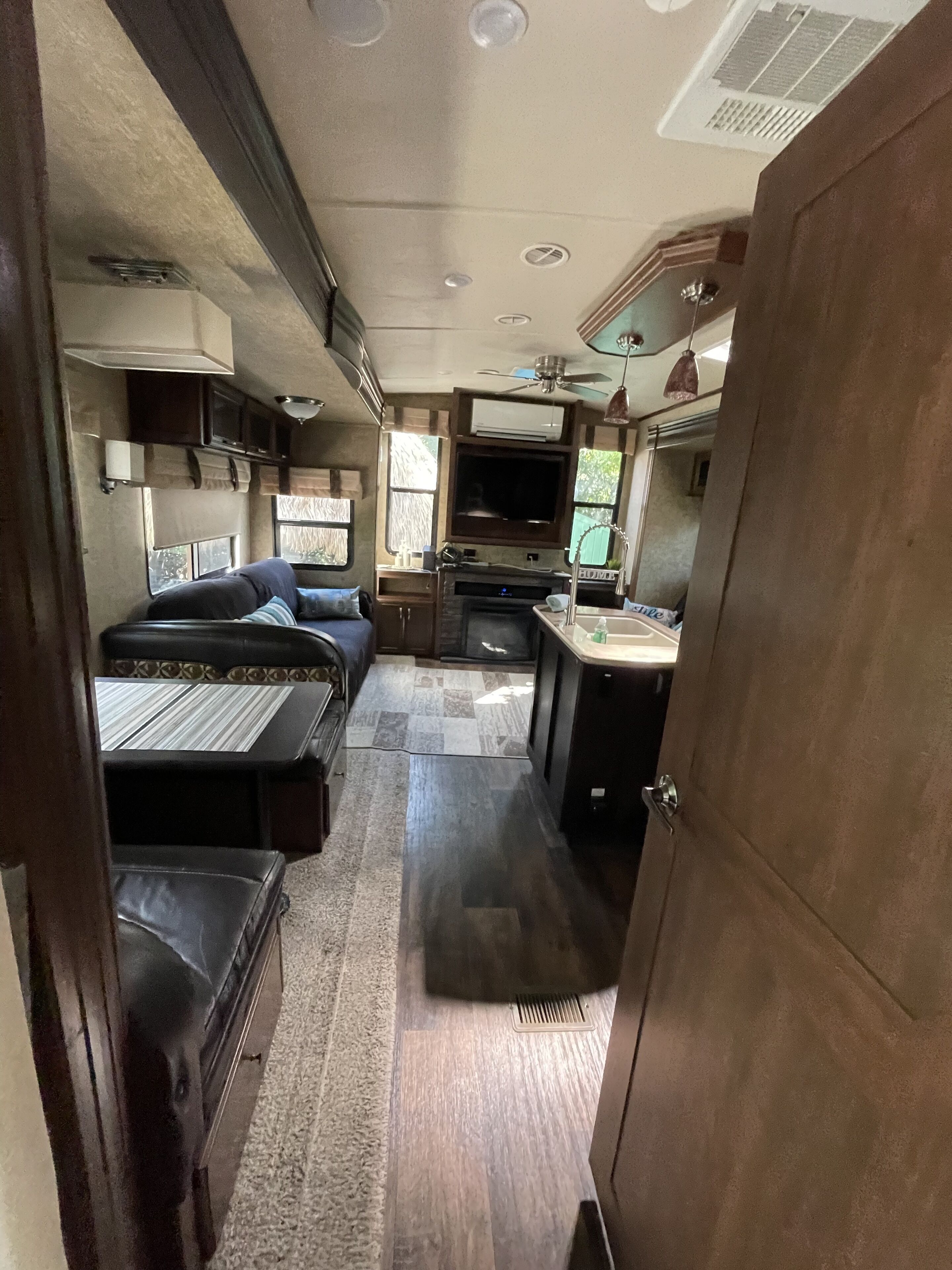 A compact RV interior with a kitchenette, a bed, and a seating area.