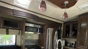 A compact RV kitchen with a central island, stainless steel appliances, and a small seating area. - Paradise in Key Largo Florida 2 (Key Largo)