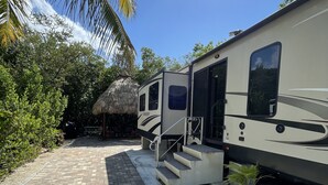 A stationary RV with a covered porch area, a brick pathway, and surrounding greenery. - Paradise in Key Largo Florida 2 (Key Largo)