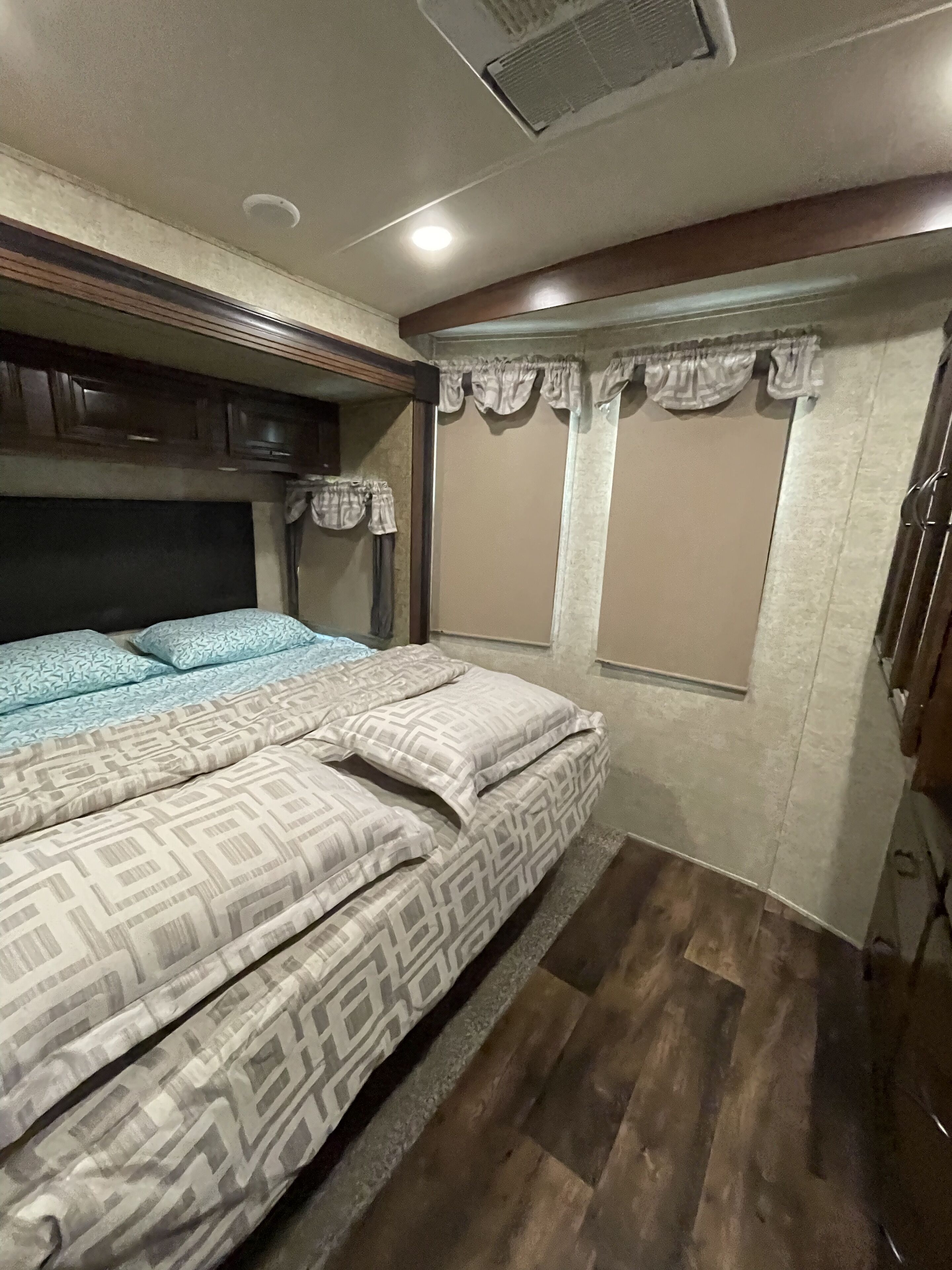 Ein Schlafzimmer mit einem Bett, einem Holzkopfstück, Vorhängen und einem Fenster.