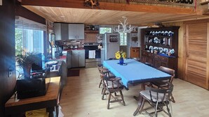 A rustic wooden interior with a dining area featuring a blue tablecloth and wooden chairs. - Lake House on Great Moose Lake with dock, swimming area, boat landing, and more! (Hartland)
