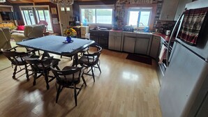 A spacious kitchen with a dining area, wooden flooring, and a view of the outdoors. - Lake House on Great Moose Lake with dock, swimming area, boat landing, and more! (Hartland)