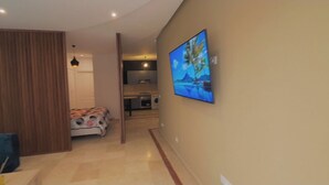 A modern living room with a flat-screen TV mounted on the wall, a sofa, and a dining area with a table and chairs. - Ravishing Studio (Casablanca)