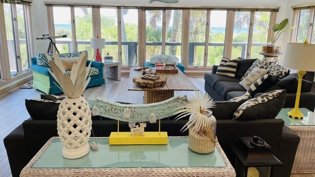 A spacious living room with a large window, a telescope, and a variety of decorative items on a central table.