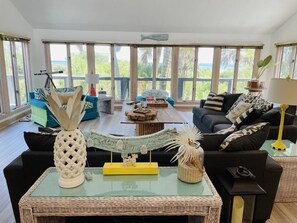 Amplio salón con un gran ventanal, un telescopio y una variedad de objetos decorativos sobre una mesa central.