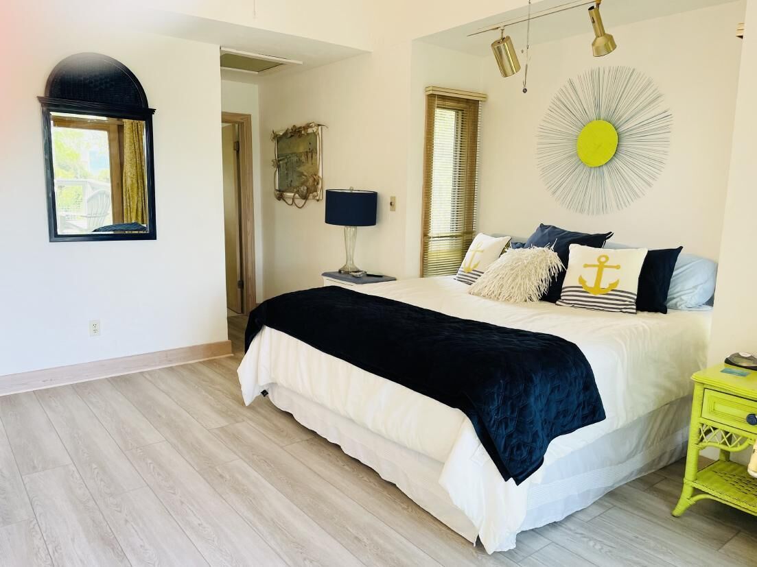Une chambre à coucher avec un lit, une table de chevet, une lampe et un élément de décoration murale.