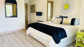 A bedroom with a bed, bedside table, lamp, and a wall decoration.