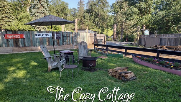 Ein Garten mit Grill, Stühlen und einem Schild mit der Aufschrift 'The Cozy Cottage'.